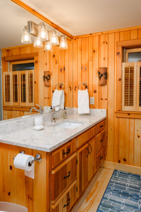 Pine wood paneling creates a rustic feel for this renovated bathroom in the cozy cabin update