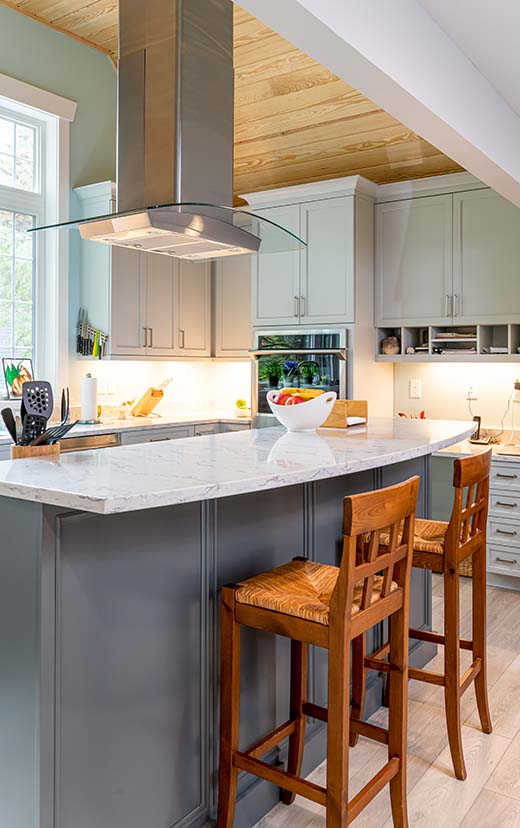In-island range with modern range hood create a industrial and contemporary feel to this kitchen remodel.