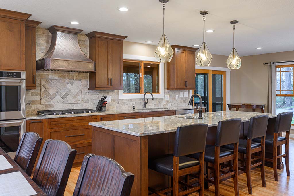 Pendant lights over a long center island complements this kitchen style